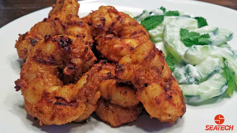 This is a photograph of curry grilled Argentine red shrimp with a yogurt based cucumber salad with mint and cilantro.