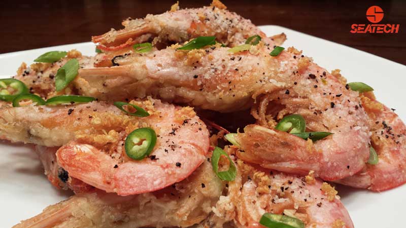 A photopraphe of salt and pepper argentine red shirmp with scallions, fried garlic and sliced sarrano peppers.